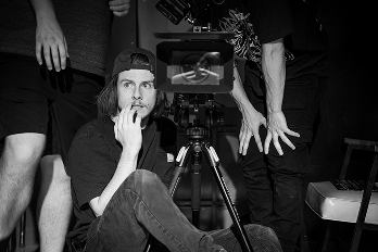Parker sitting on a dolly by a camera on set of The Collins Film photo credit: Jordan Skutar